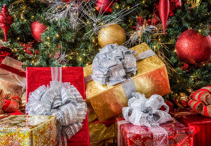 Presents in front of a Christmas tree with wrapped in red and gold 