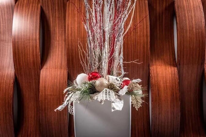 Christmas decorations in a pot against a wooden wall 